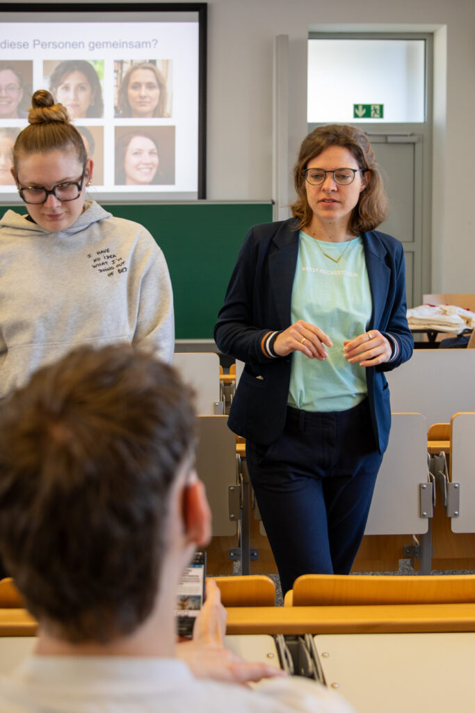 Dr. Charlotte Echterhoff gibt ein Training für Demokratiebildung. Man sieht im Hintergrund eine Präsentation und im Vordergrund Studierende.